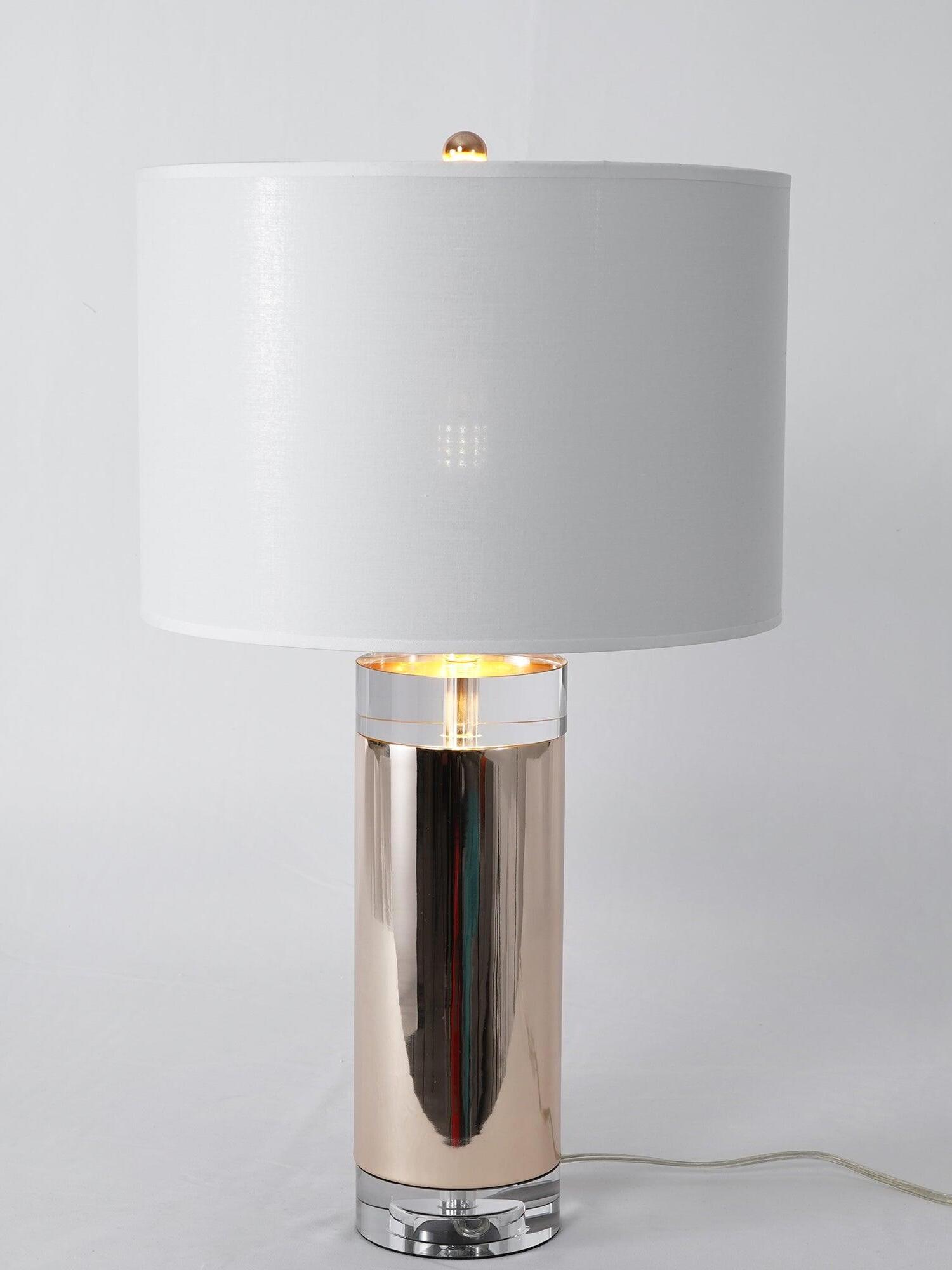 Lit white drum-shade lamp with reflective cylinder and clear round base