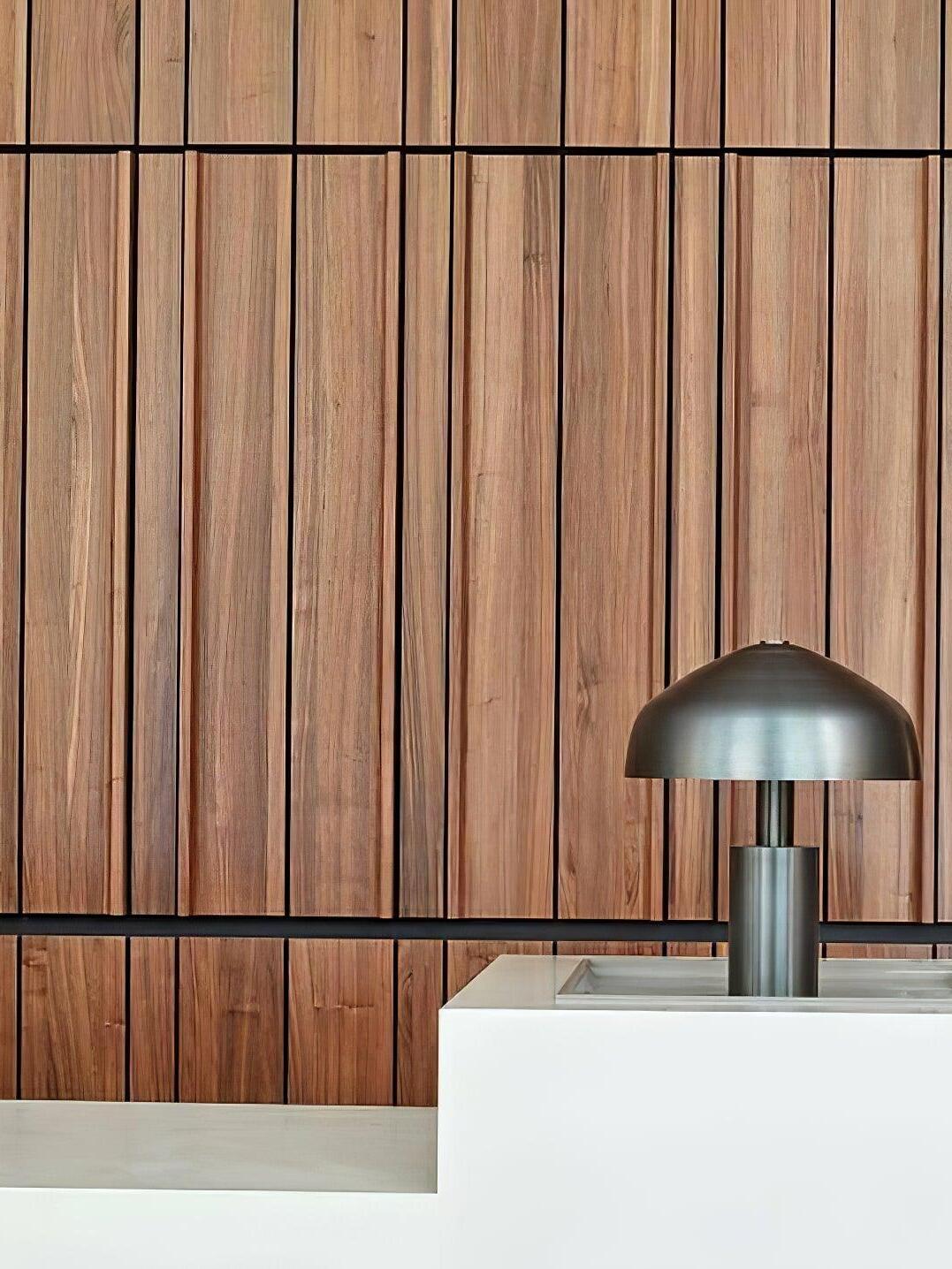 Black dome lamp on pale counter by wood wall