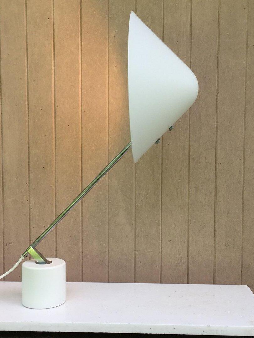 White shade turned upright on a diagonal arm beside a wood-panel wall