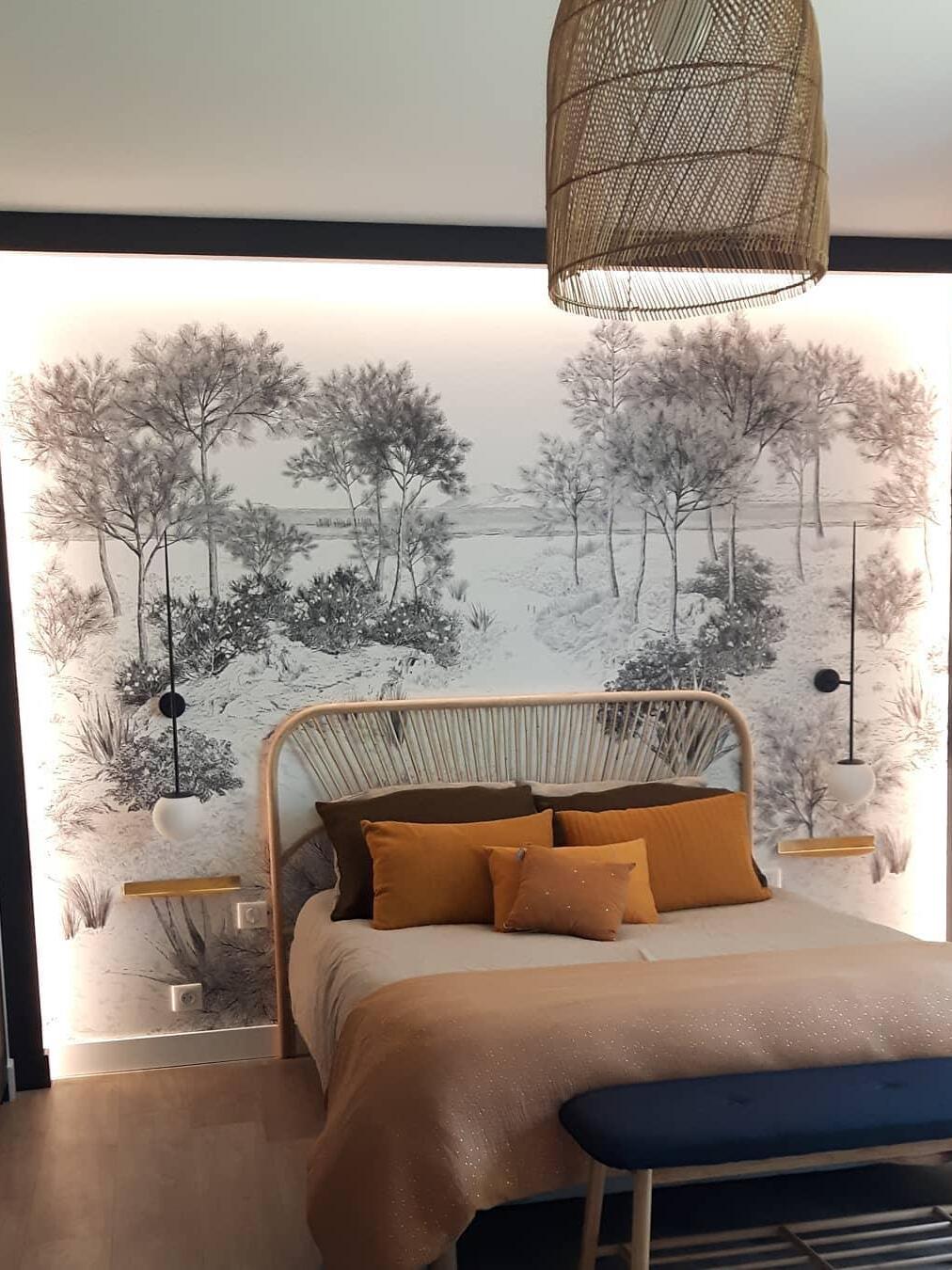 Two separate black globe wall lights beside a woven headboard against a forest mural, with small shelves below