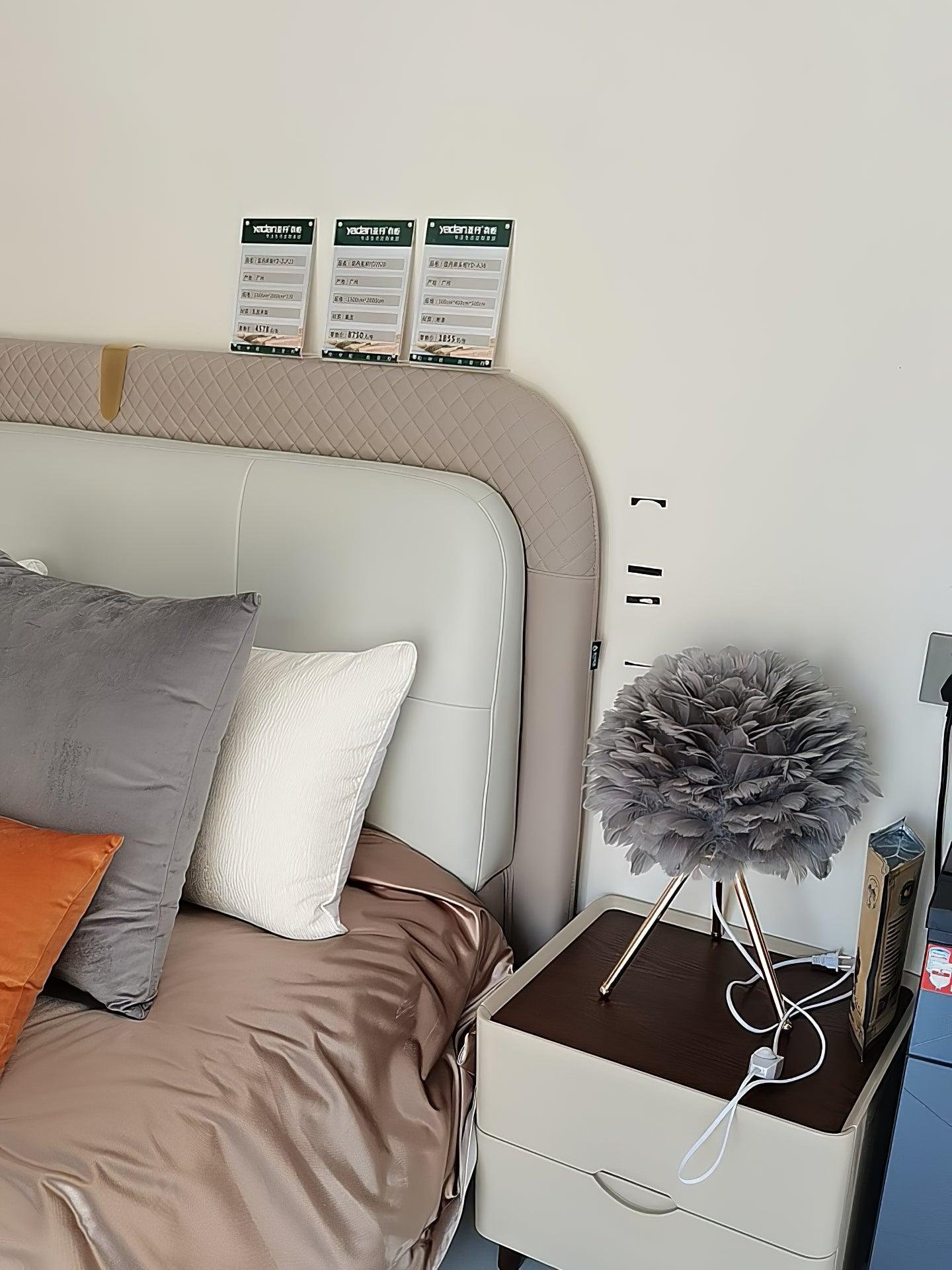 Grey feather lamp on chest by bed