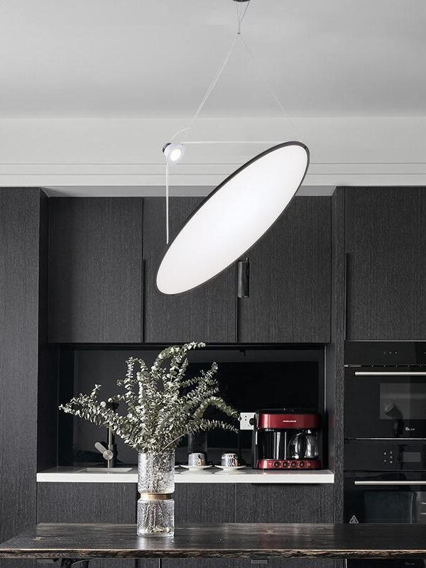Illuminated circular disc pendant above a counter