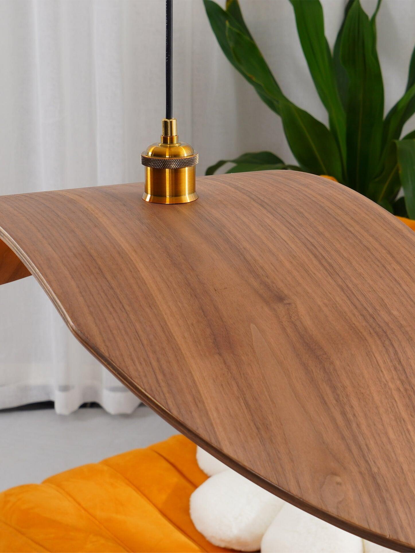 Close view of the curved wood-grain wing and gold-tone cable fitting with plants in the background