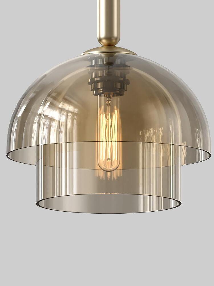 Close-up of a two-tier domed glass shade and lower cylinder around a filament bulb, with gold-tone upper fitting