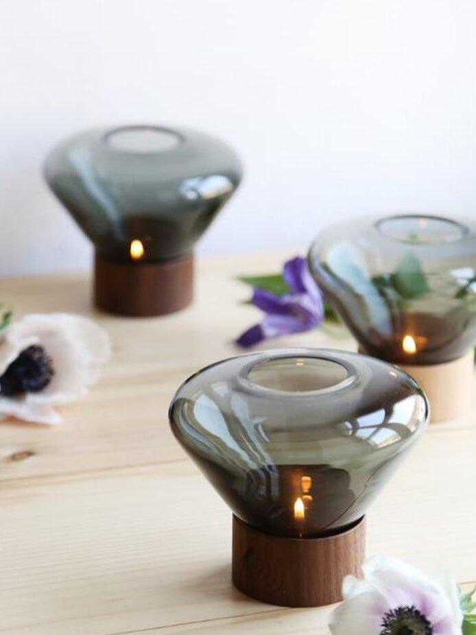 Three small smoky rounded glass lamps on wood bases arranged near flowers