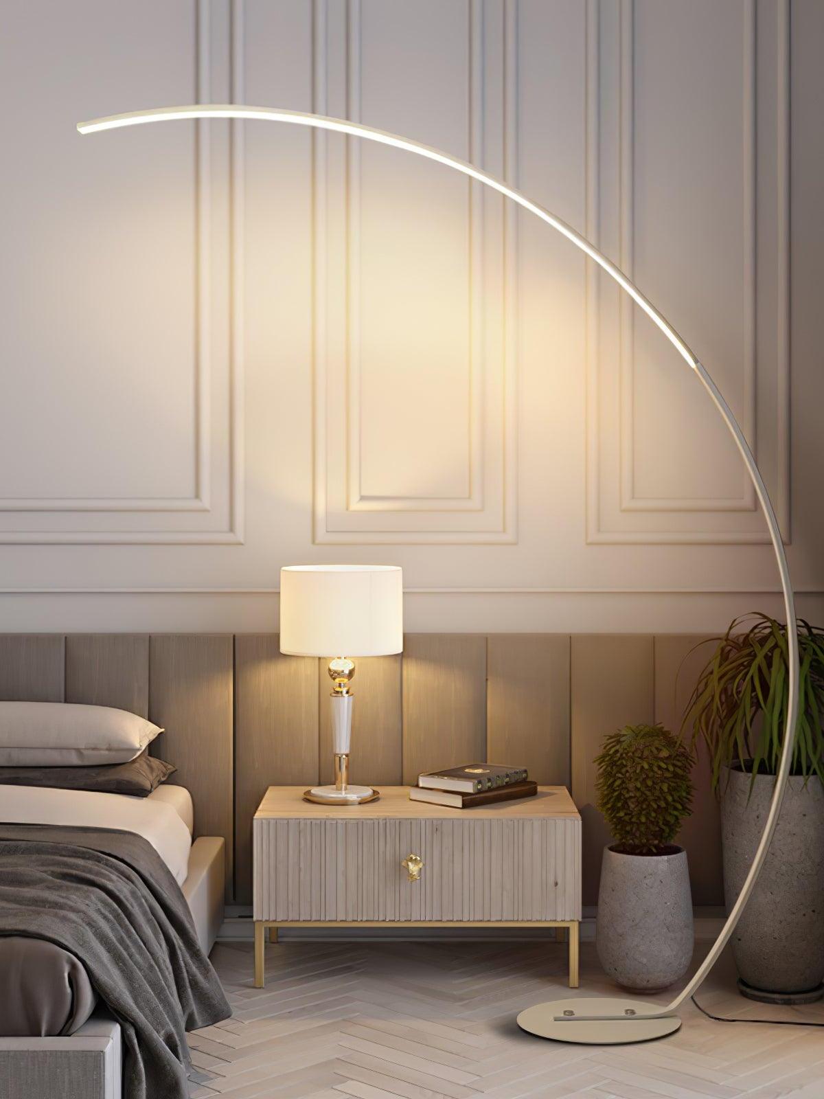 White arc LED floor lamp beside bed