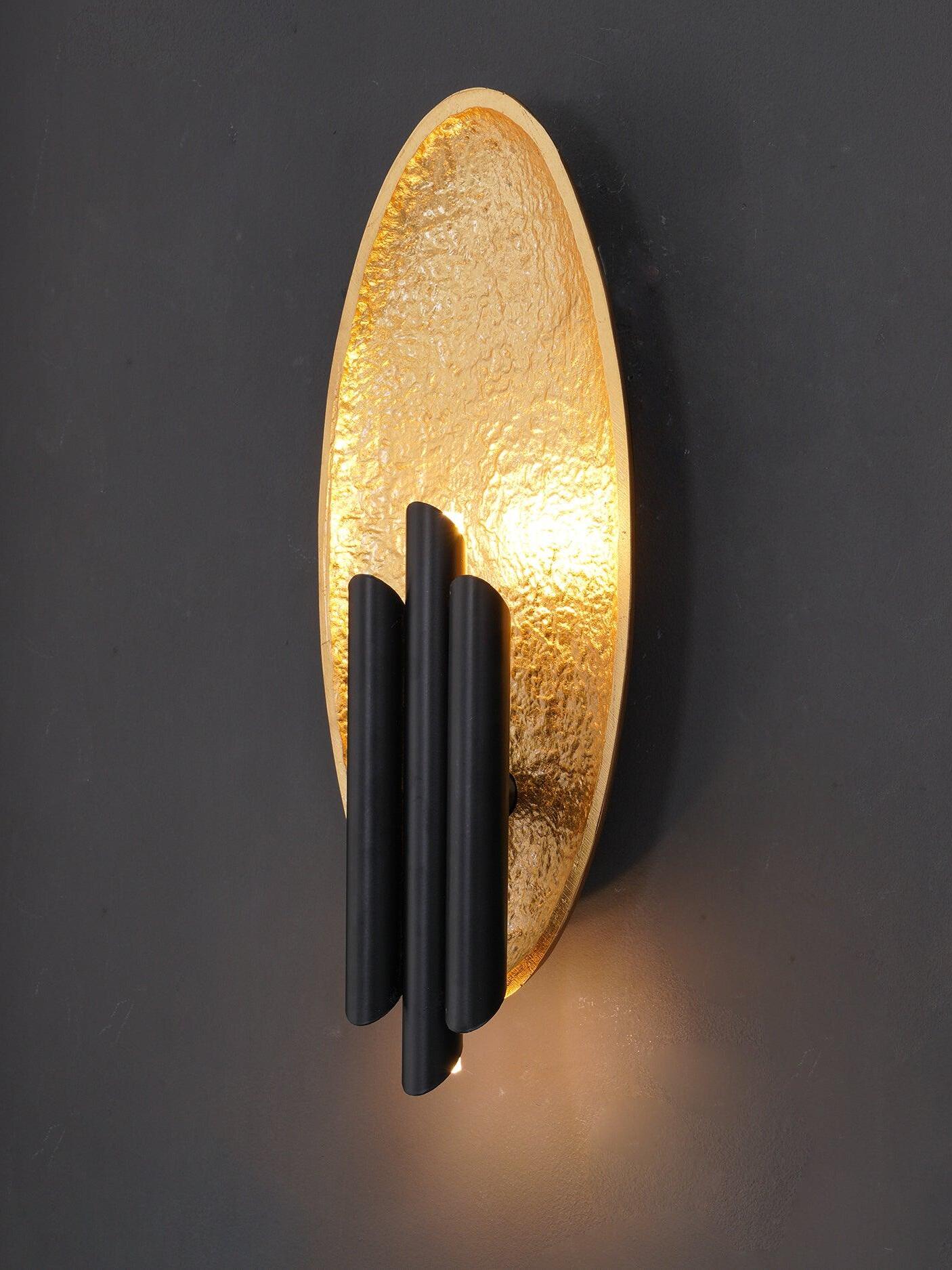 Close lit gold-tone textured oval and dark tube details