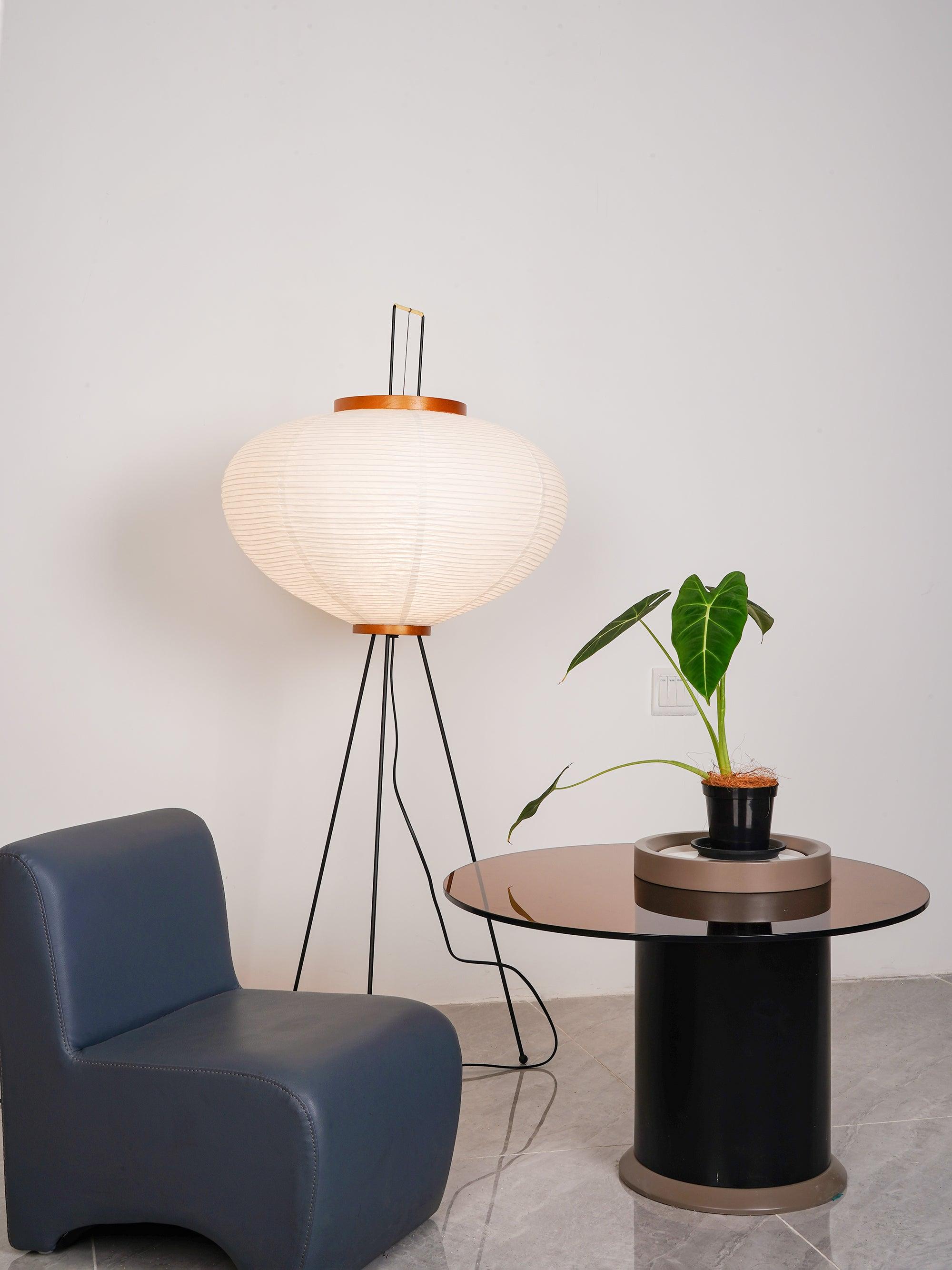 Round paper lamp beside blue chair and dark side table