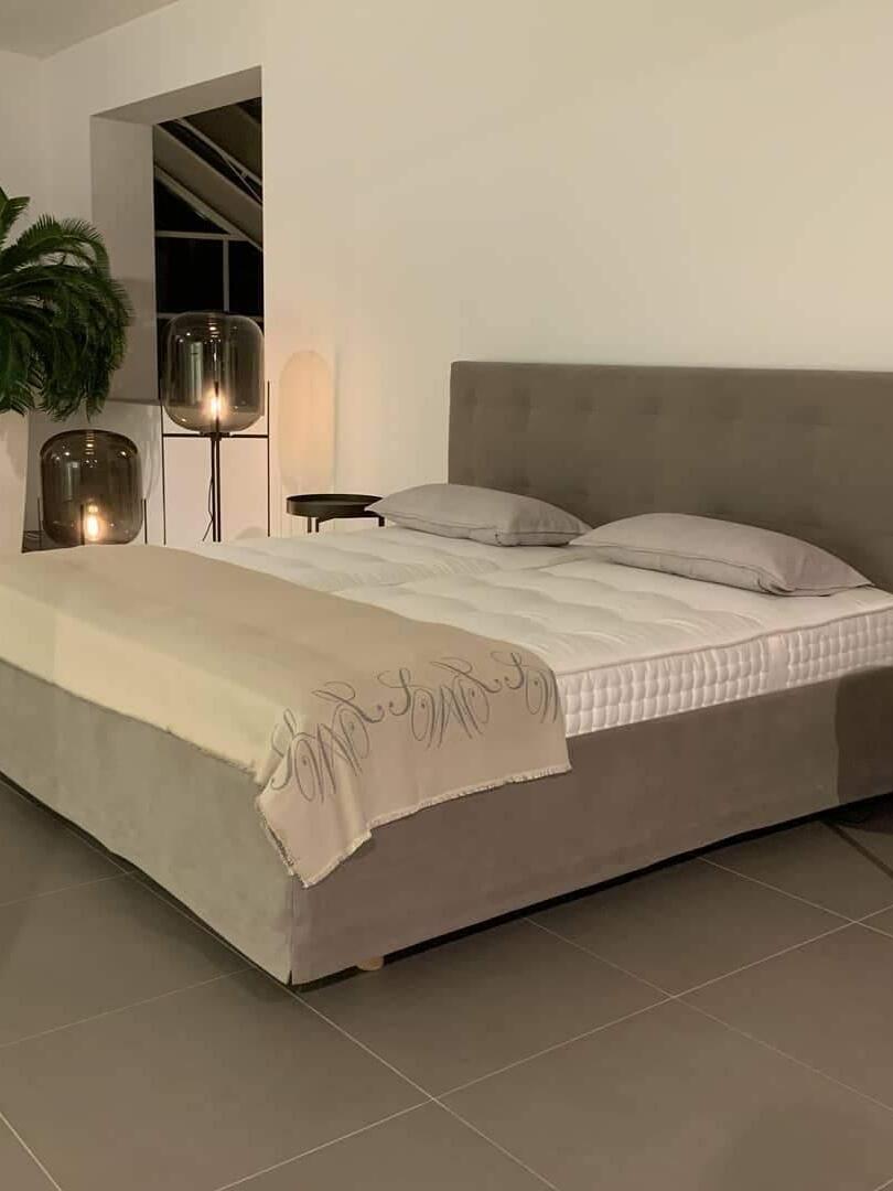 Tall and short dark glass lamps in a neutral bedroom.