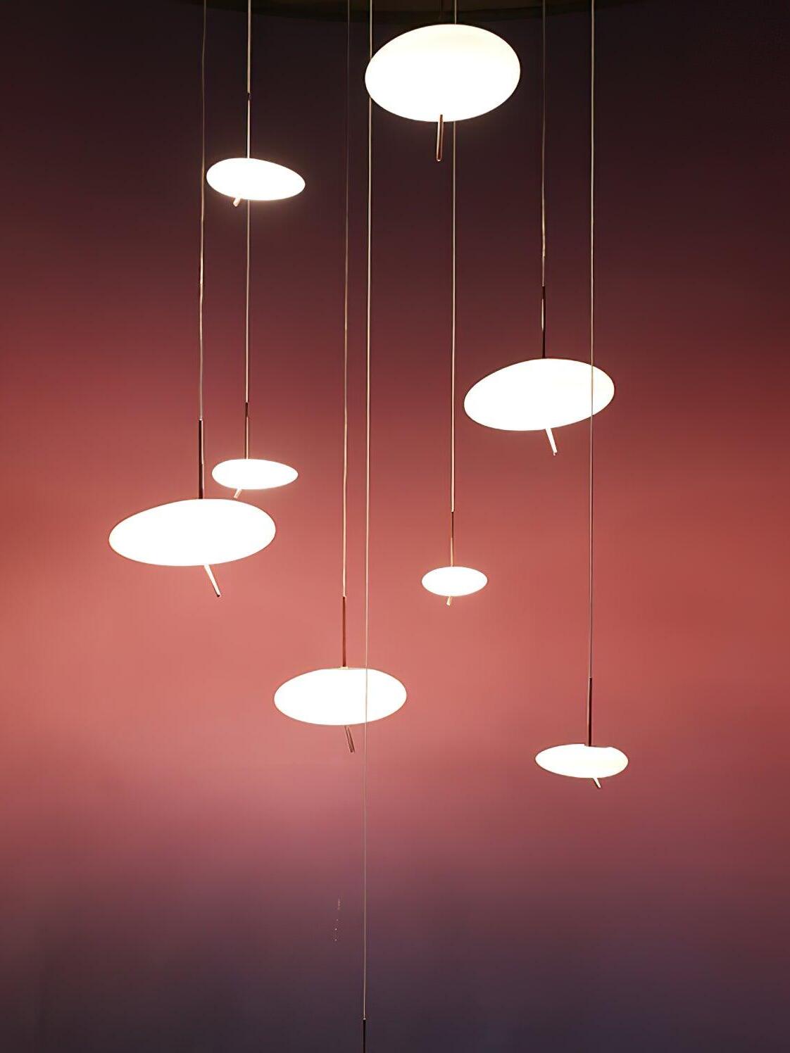Several white pebble-shaped pendant shades suspended at varied heights against a red wall