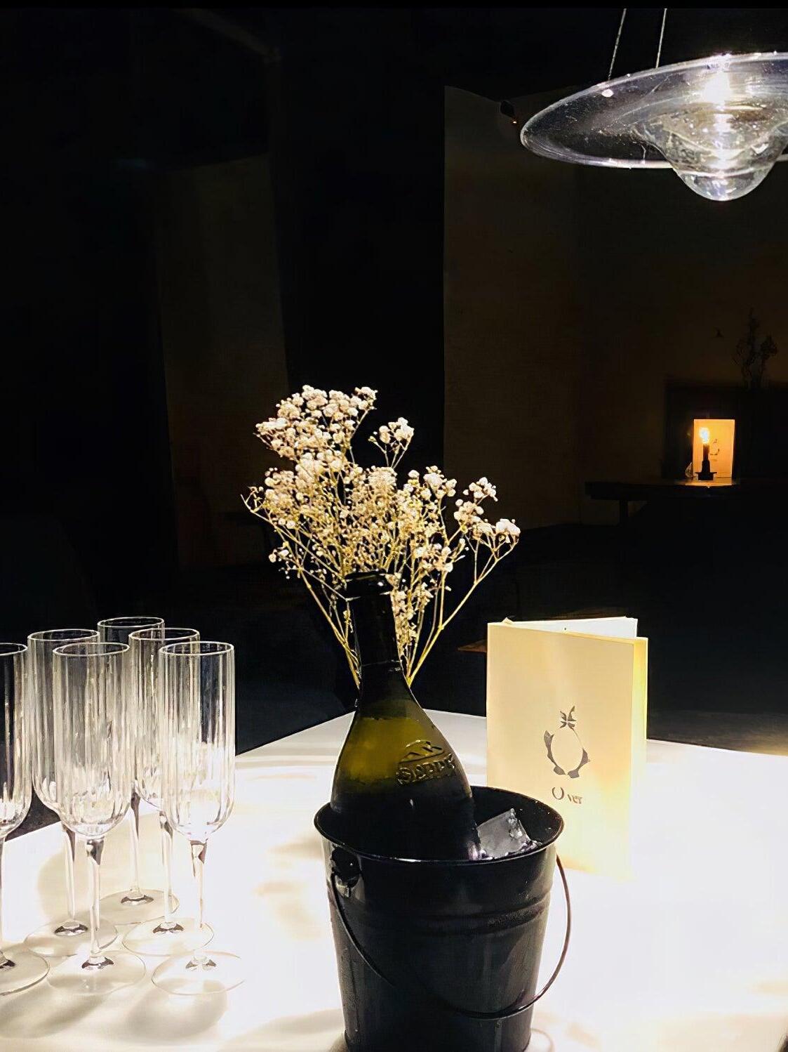 Edge of lit clear disc pendant above table flowers