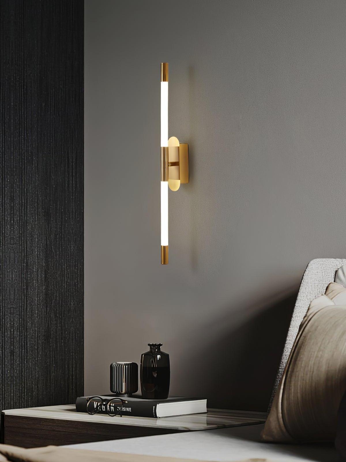 Gold Agnes wall light above a dark bedside table with books and small objects