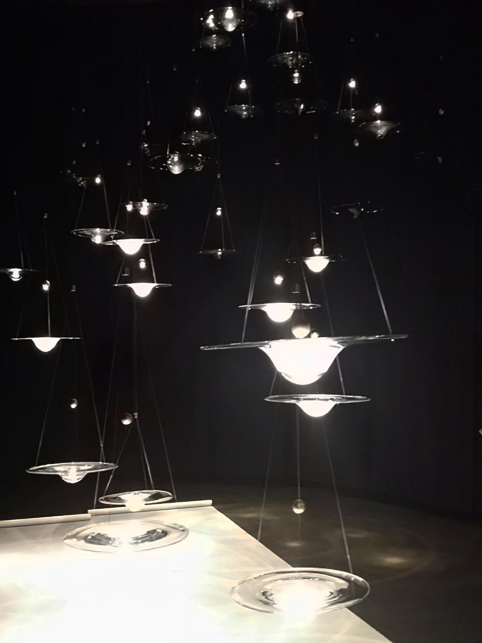 Lit clear disc pendants above white surface in dark room