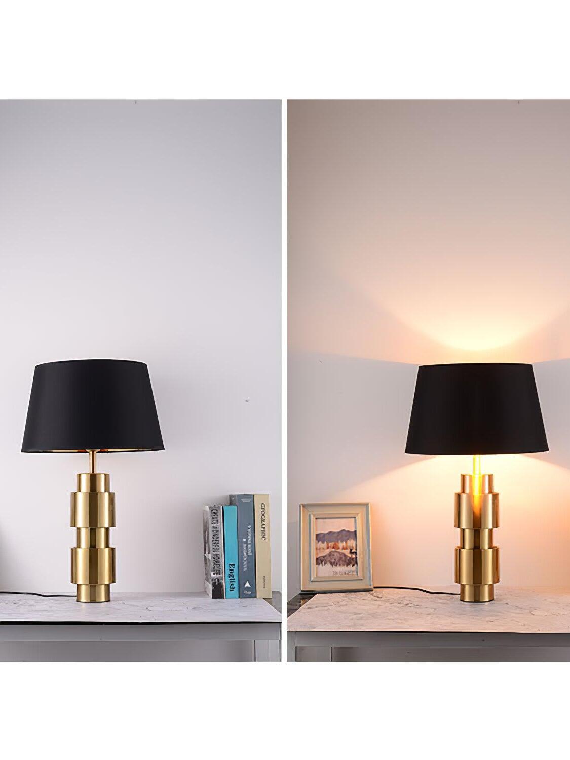 Side-by-side views of the Jean table lamp unlit and lit on a surface with books and a photo