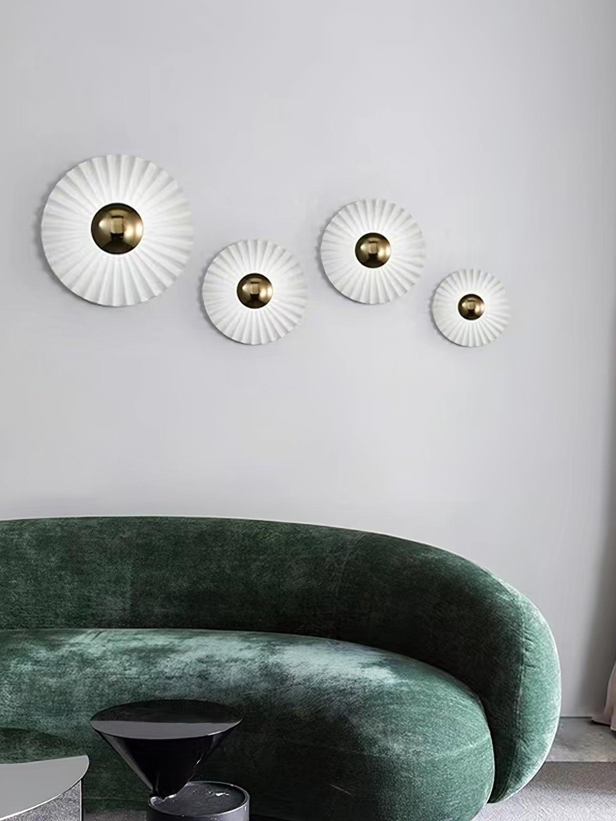 Four illuminated radial wall lights behind green sofa