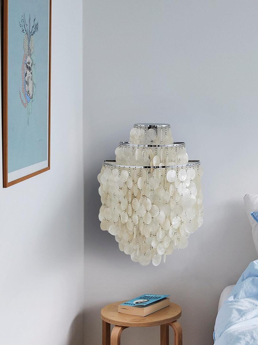 Three-tier shell wall fixture above stool beside bed