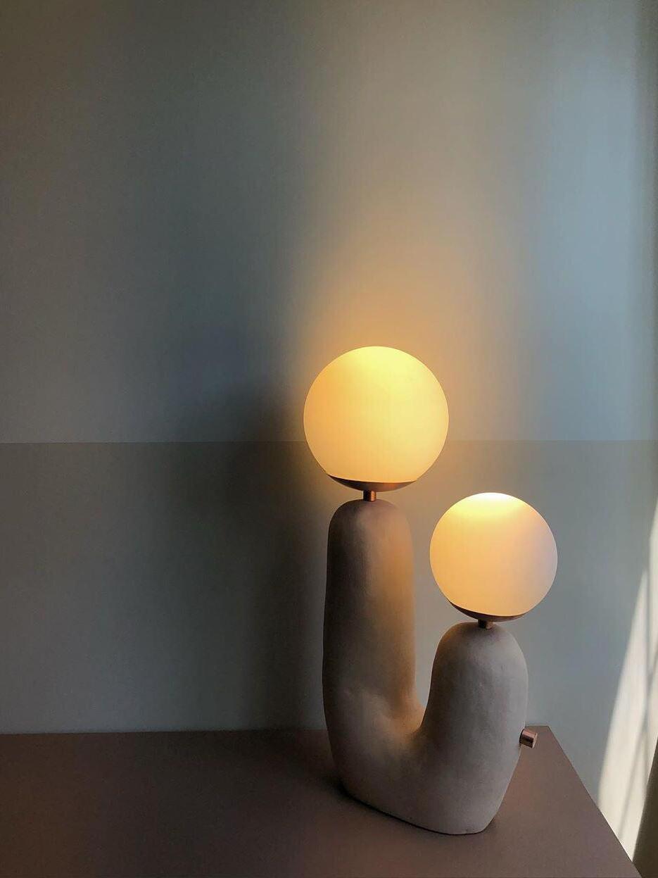 Illuminated grey-looking double-globe lamp in a room