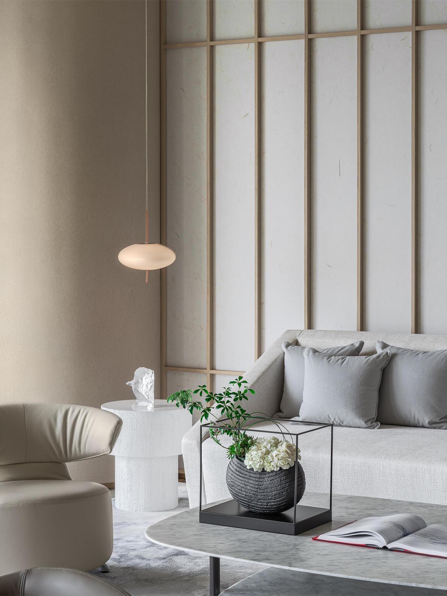 Small white pendant beside a window and pale sofa in a living room