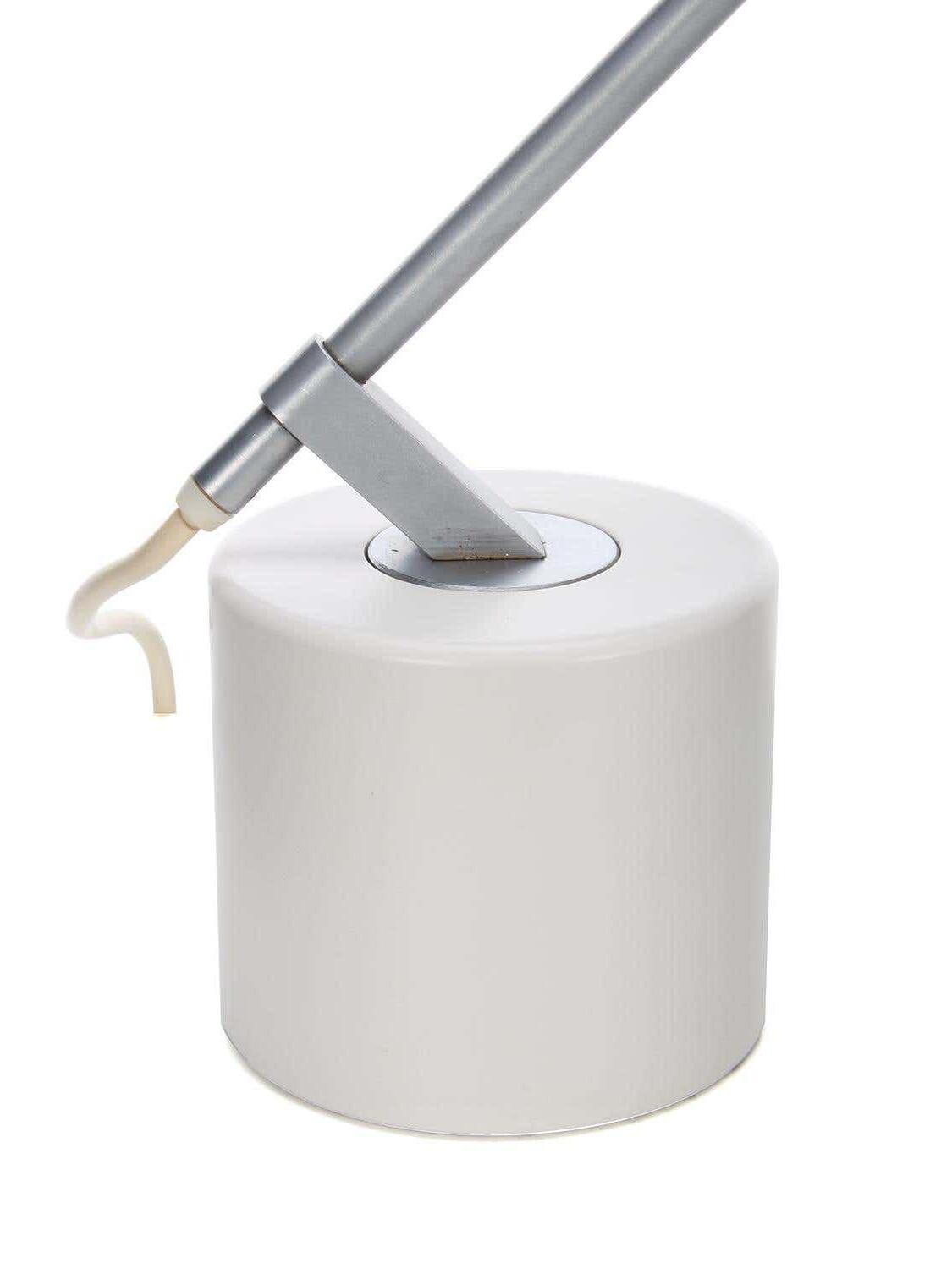 Close-up of silver-tone arm fitting, pale cord and smooth white cylindrical base