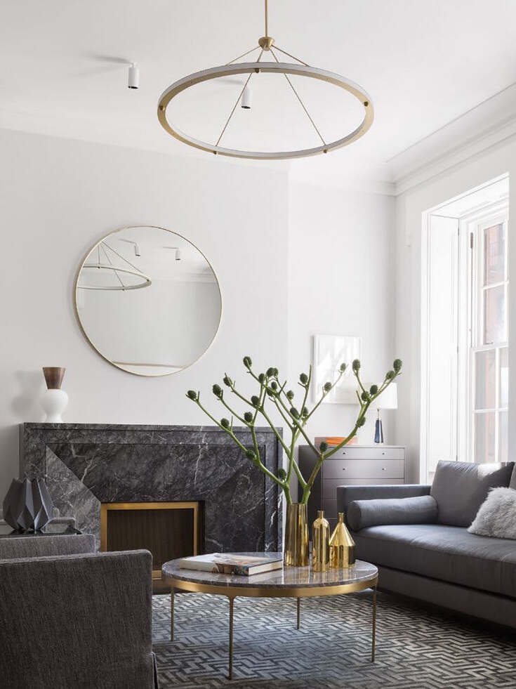 Gold circular pendant in living room beside fireplace