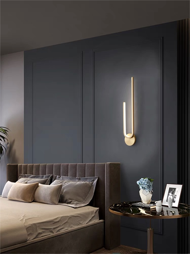 Inverted gold-tone arch with its mount below the upward arms beside a gray bed and round bedside table