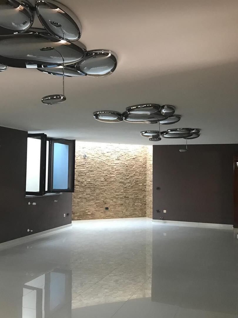 Two reflective ceiling groups in sparse room with brick wall and glossy floor