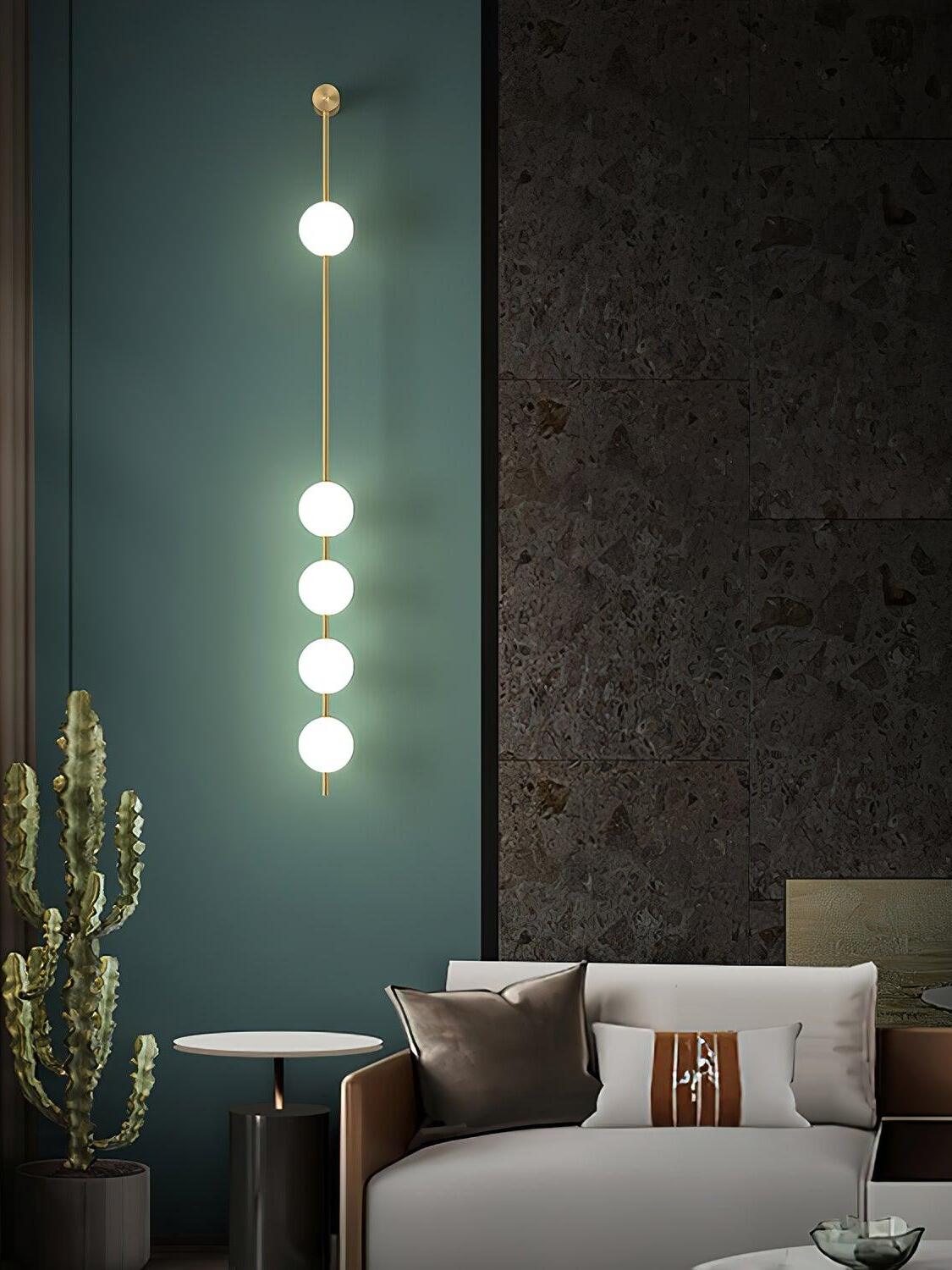 Five-globe wall light on a teal wall beside a cactus, small table and sofa