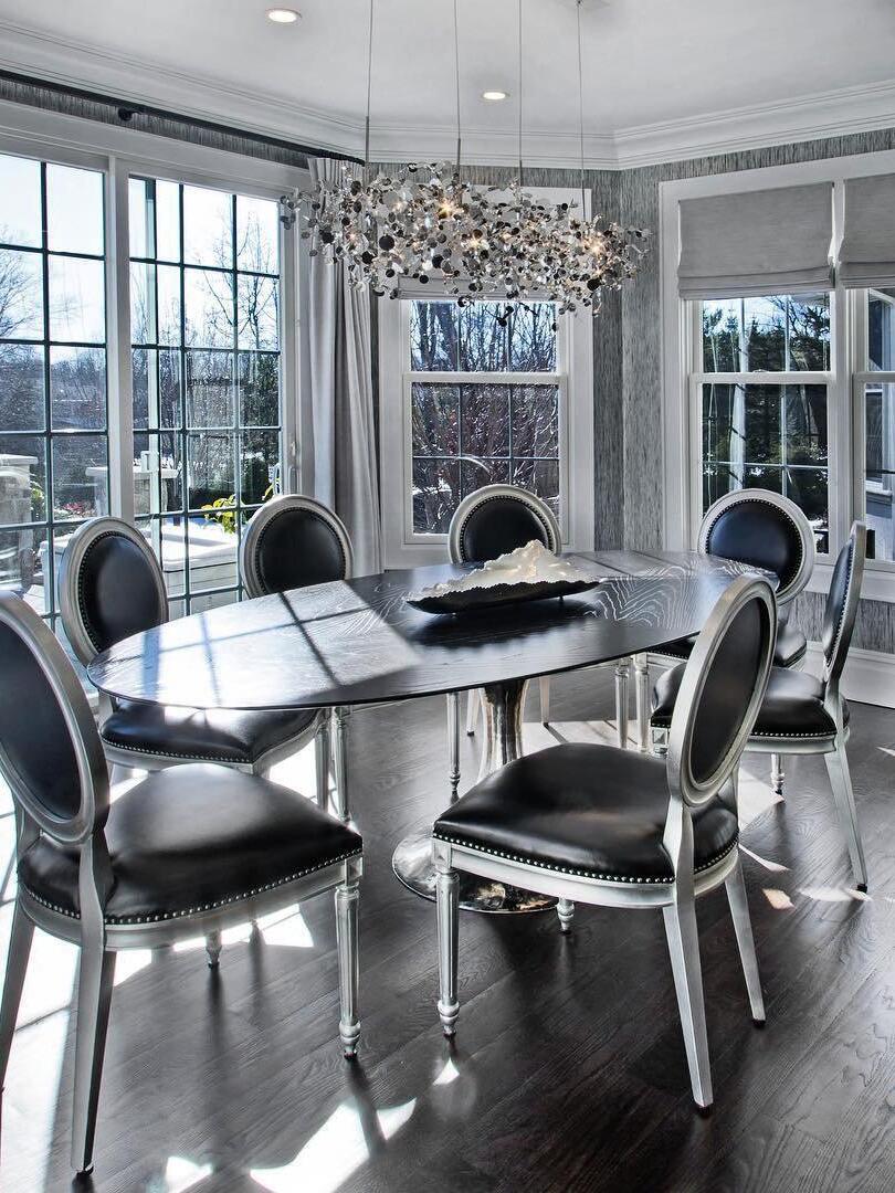 Silver disc chandelier above a formal dining table by windows