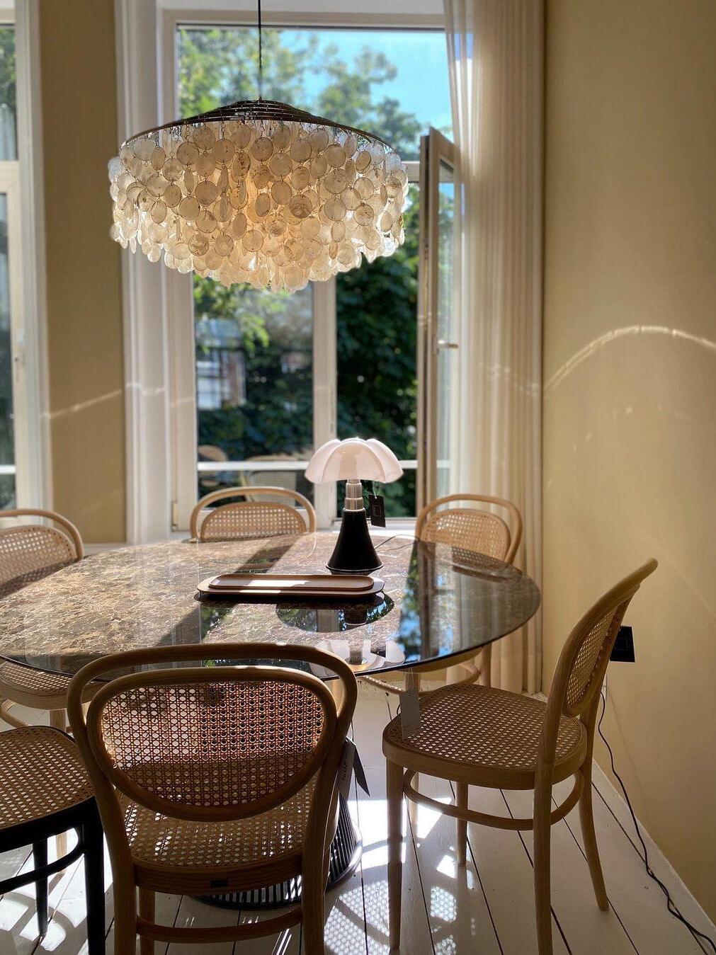 White shell discs over a dining table near a tall window