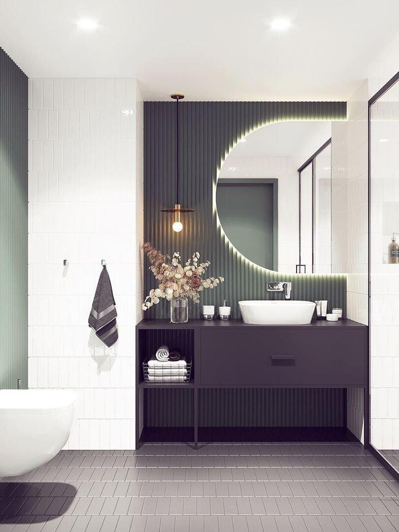 Brass-tone disc pendant beside a round illuminated bathroom mirror and white vessel basin