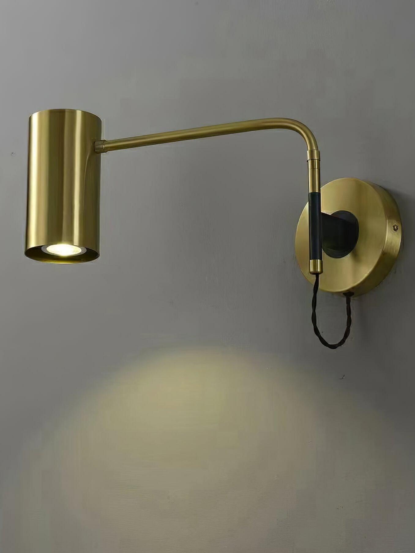 Lit brass-tone wall light with cylindrical shade and round plate
