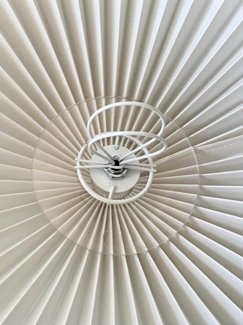 Close view of concentric shade-support rings and central fitting beneath the pleated shade