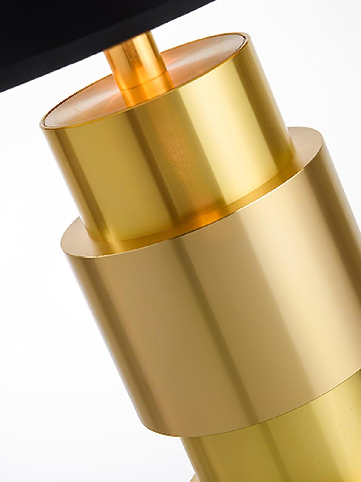 Angled close-up of the reflective gold-tone cylinders and stem beneath the black shade