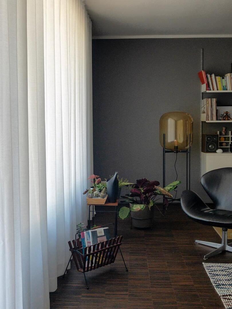 Amber glass floor lamp near a bookshelf and a dark lounge chair.