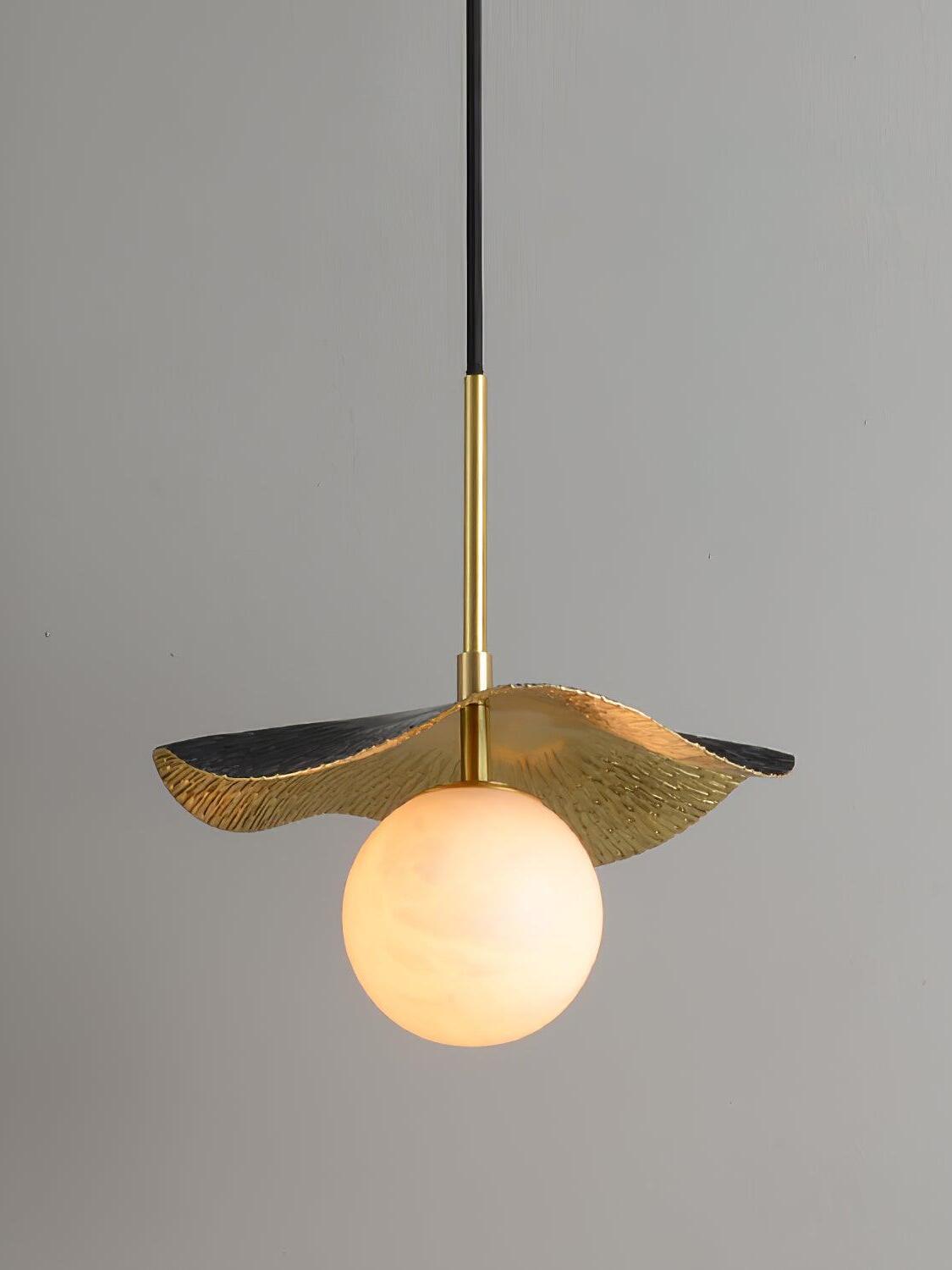 Lit pale globe beneath black and brass leaf shade