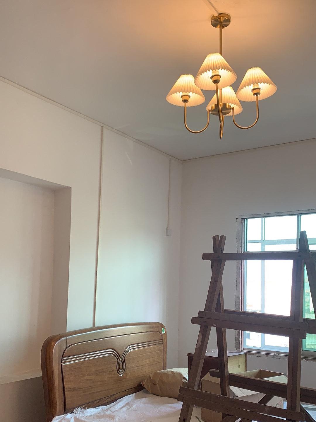 Warm-looking chandelier above a wooden headboard beside a ladder and window