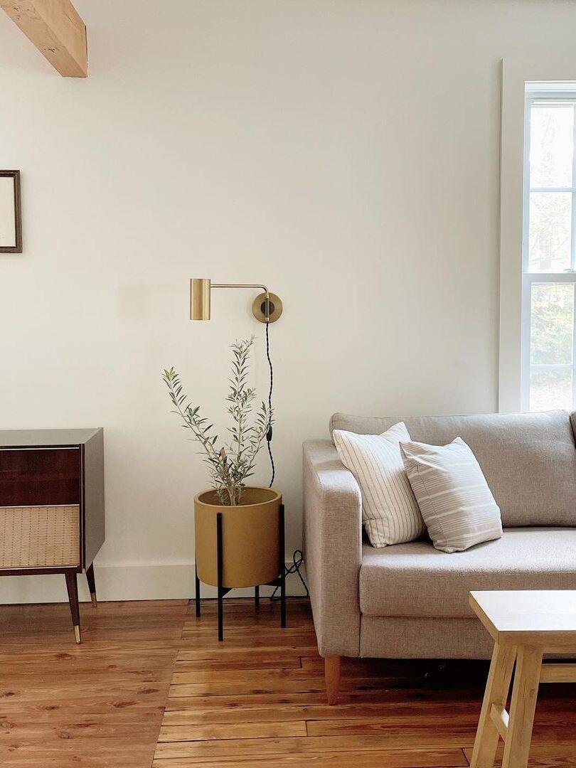 Brass-tone wall light between console and pale sofa
