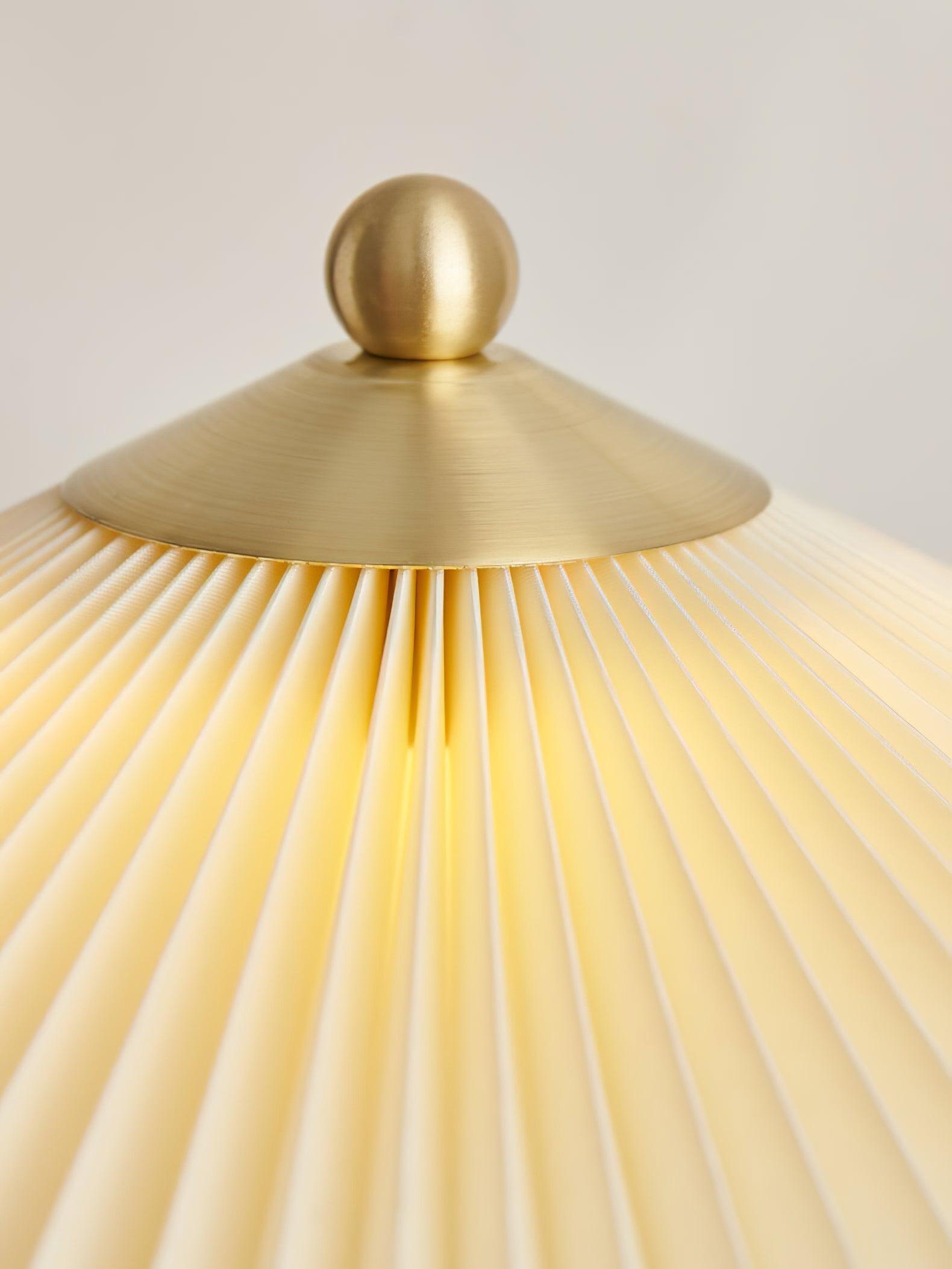 Close-up of the gold-tone ball finial and conical cap above the pleated shade