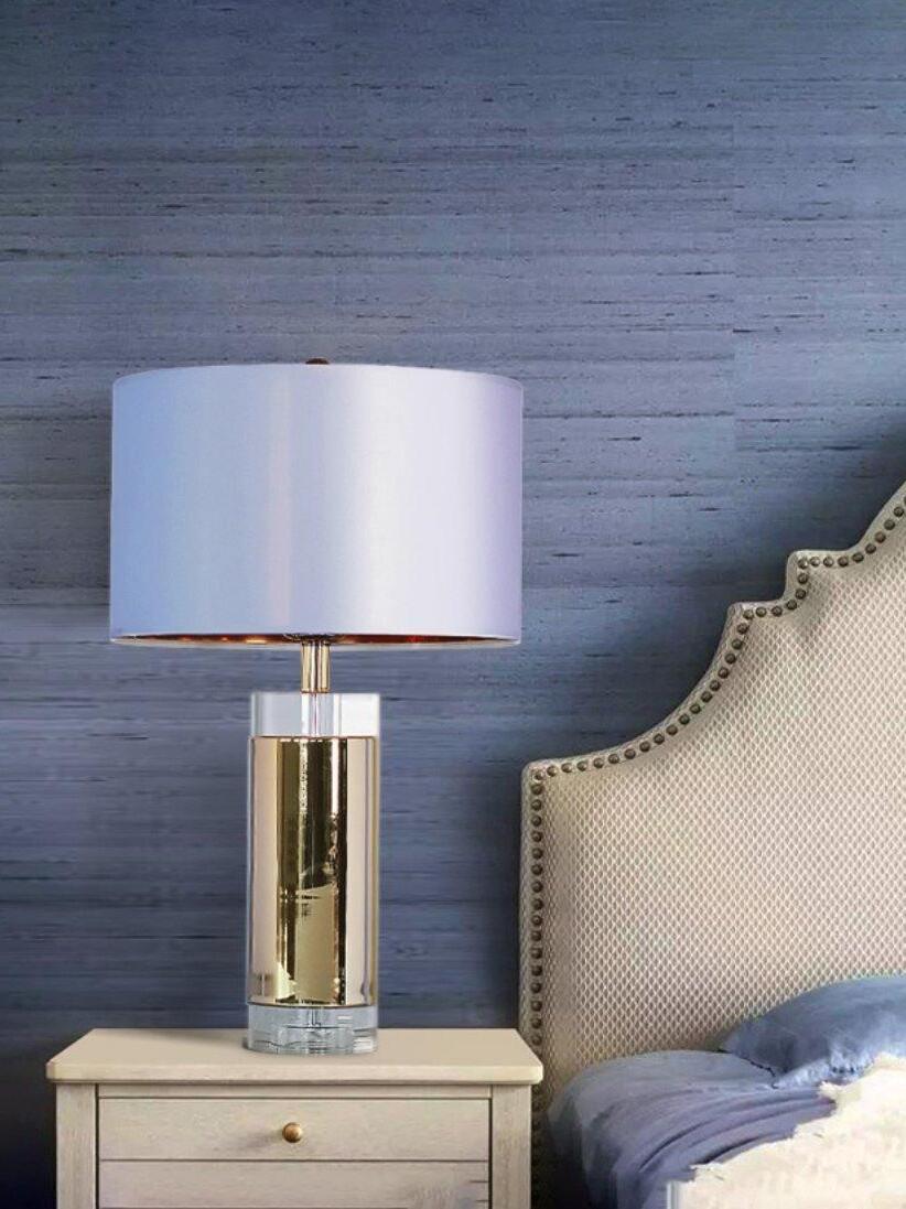 White drum-shade cylindrical lamp on bedside cabinet against blue wall