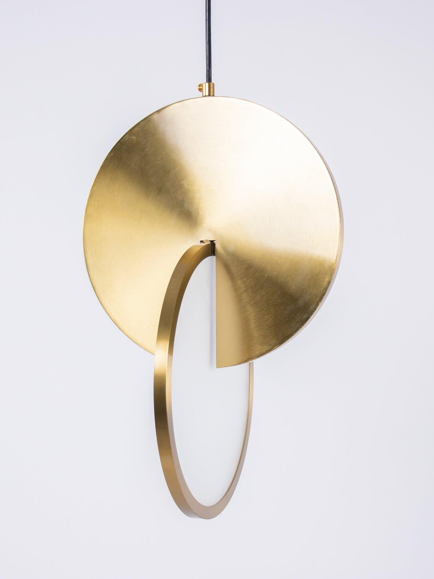 Angled close view of intersecting gold circular panel and white diffuser on a black cord