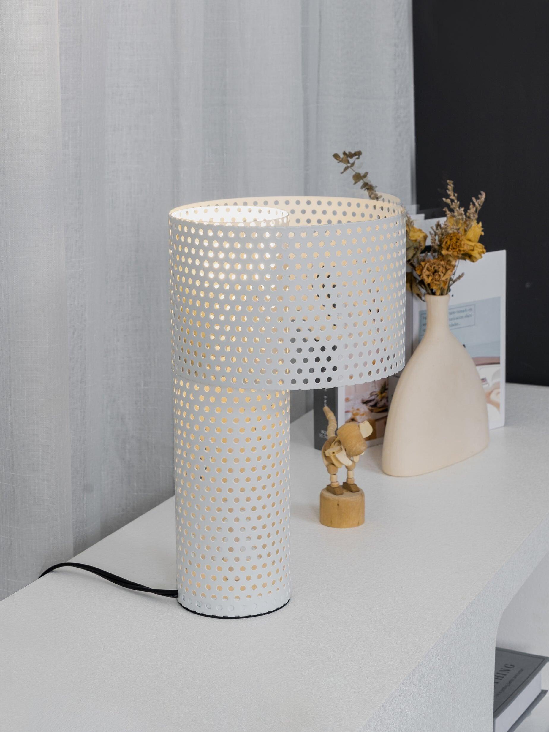 White perforated lamp and vase on pale tabletop