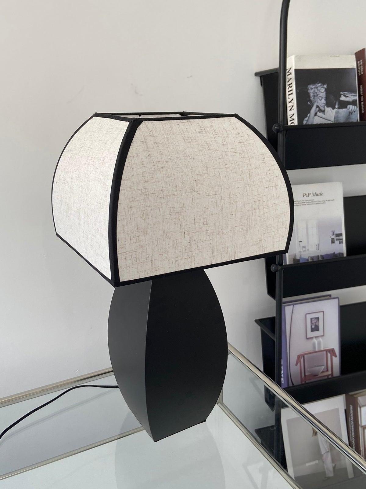 Side view of black base and fabric shade near shelving