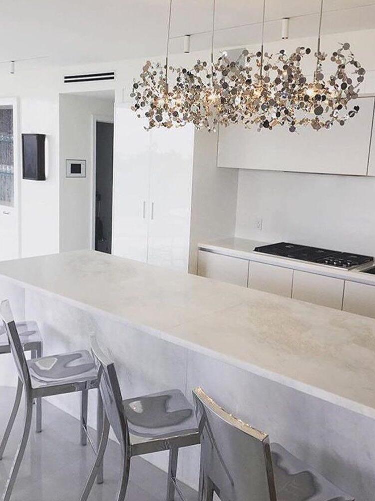 Long silver disc chandelier above a white kitchen island