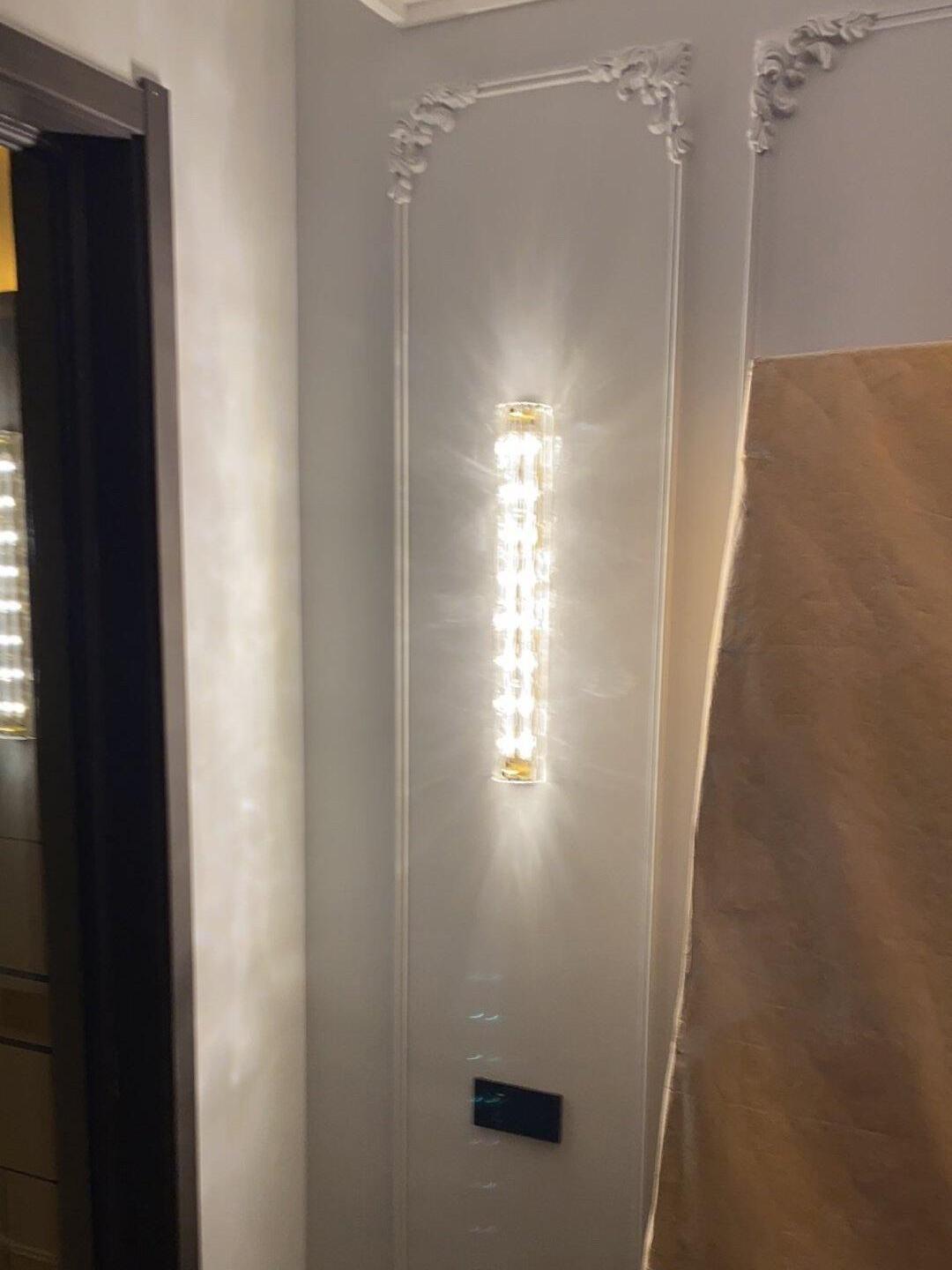 Glass wall light on ornamental white wall panel