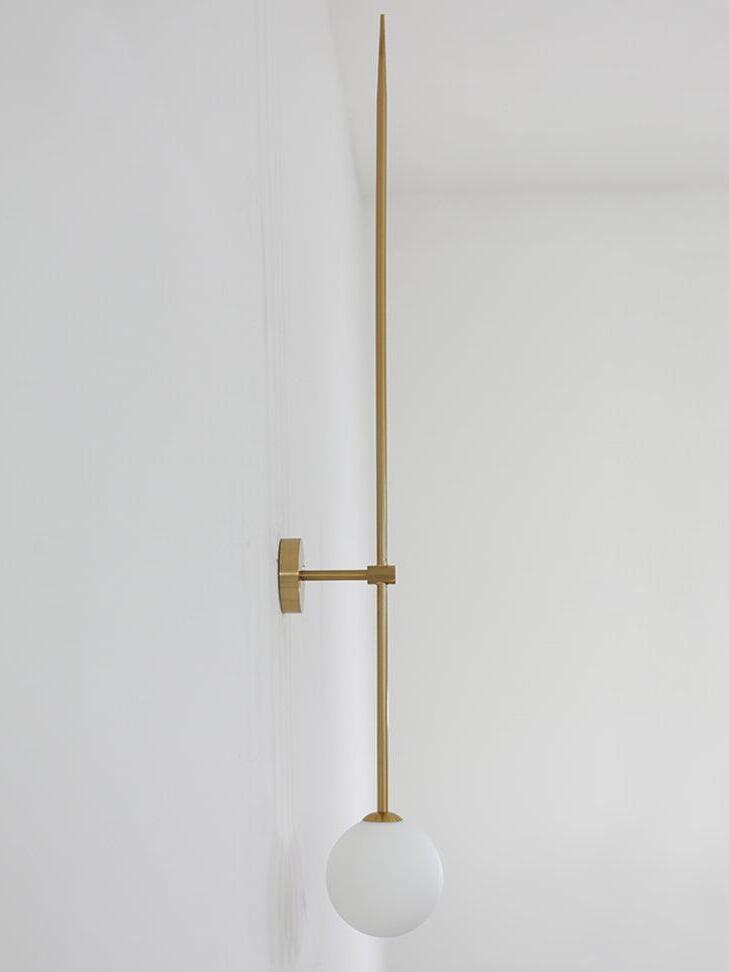 Side view of an unlit gold-tone rod wall light with a short arm and white globe
