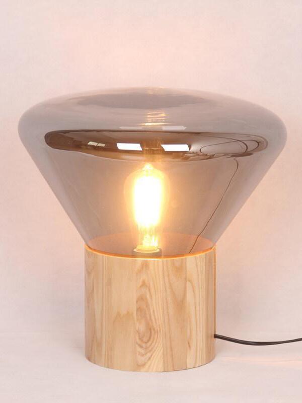 Smoke-tinted flared glass lamp with lit bulb, wood base and black lead