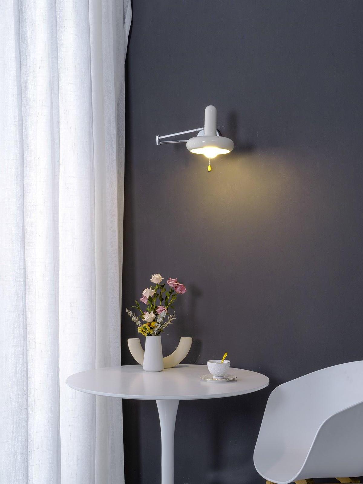 Lit cream wall light above round table on dark wall