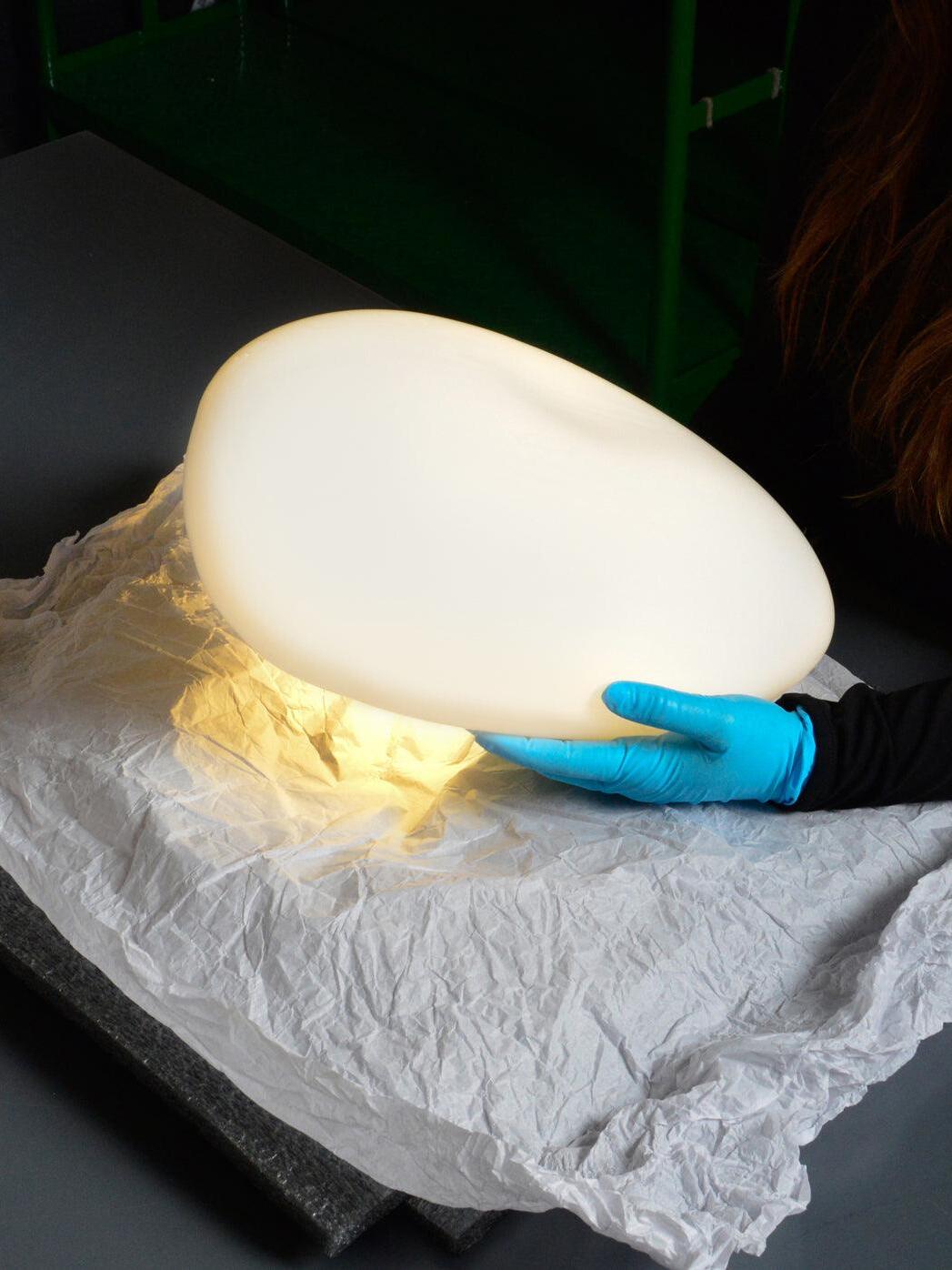 Pale glowing pebble-shaped component in workshop photo