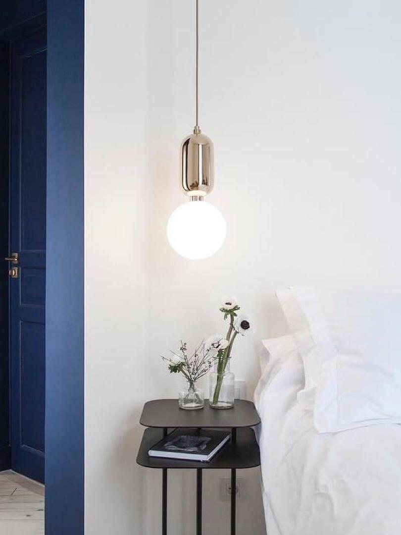 Reflective-cap pendant beside a bed