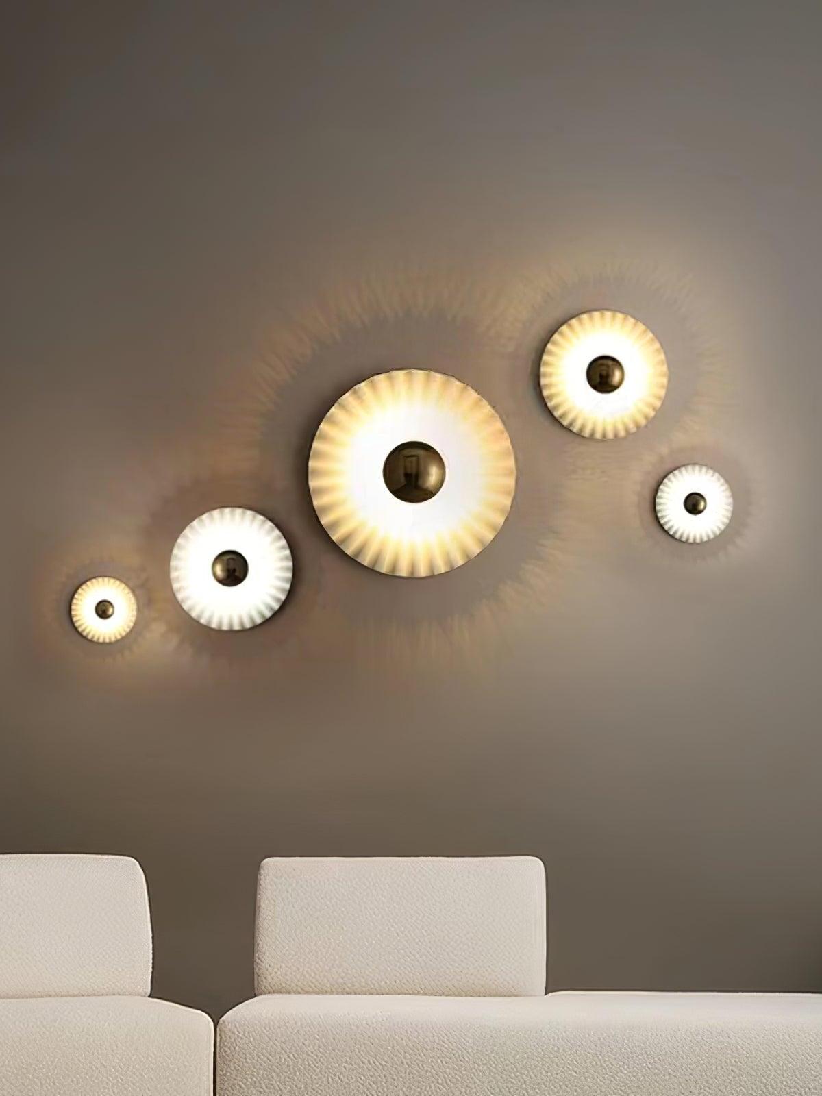 Four lit pleated wall discs above white seating